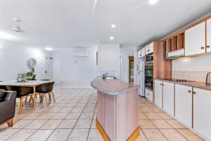 a kitchen with white cabinets and a table and a counter at Magnificence At Airlie in Airlie Beach
