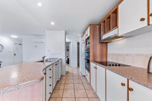 a kitchen with white cabinets and marble counter tops at Magnificence At Airlie in Airlie Beach