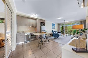 a kitchen and living room with a table and chairs at Alpha 8 on Waterson - Airlie Beach in Airlie Beach