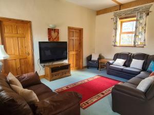 een woonkamer met banken en een flatscreen-tv bij Swallow Cottage in Whitland