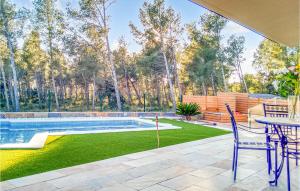 een patio met een tafel en stoelen en een zwembad bij 3 Bedroom Stunning Home In Cabra Del Camp in Cabra del Camp