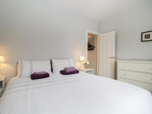 a white bedroom with a large white bed with purple pillows at Banks Place in Keswick