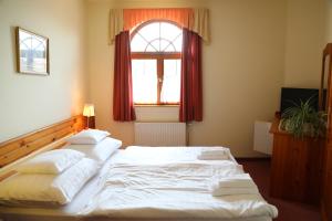 a bedroom with a large white bed with a window at Hajdú Kastély Hotel in Hajdúszoboszló