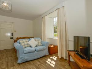 a living room with a blue couch and a television at Tregonhawke Farmhouse in Cawsand