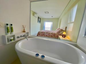 a bath tub in a bathroom with a mirror at Apartamento Guarujá morro do Maluf de frente ao mar! in Guarujá +31 photos