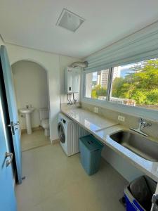 a kitchen with a sink and a washing machine at Apartamento Guarujá morro do Maluf de frente ao mar! in Guarujá