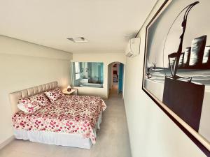 una camera con un letto e una foto appesa al muro di Apartamento Guarujá morro do Maluf de frente ao mar! a Guarujá