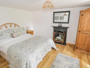 een slaapkamer met een bed en een open haard bij Mary Kate's Cottage in Narin