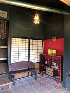 a room with a bench and a red wall at 自然の中の古民家ゲストハウスちゃいはな庵 Organic county style classic house Chaihana an in Lake Toya