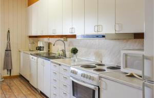 a kitchen with white cabinets and a stove and a microwave at 5 Bedroom Pet Friendly Home In Sdra Rdom 