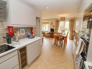 a kitchen with white cabinets and a dining room at Church View in Bourton on the Water