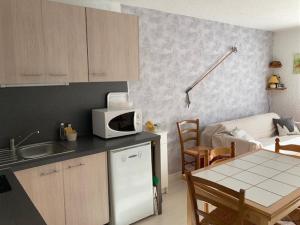 a kitchen with a white microwave and a table with a couch at Studio Corrençon-en-Vercors, 1 pièce, 4 personnes - FR-1-515-124 in Corrençon-en-Vercors