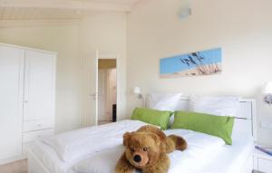 un orsacchiotto seduto su un letto in una camera da letto di 3 Bedroom Lovely Home In Dagebll a Dagebüll