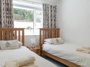 two beds in a room with a window at 2 Rockmount in Salcombe