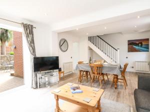 uma sala de estar com uma mesa de jantar e uma televisão em The Pines em Weymouth