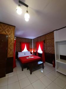 1 dormitorio con 1 cama con sábanas rojas y cortinas rojas en Hof Gorei Beach Resort Davao, en Samal