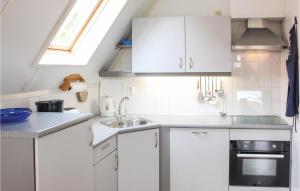 una piccola cucina con armadi bianchi e una finestra di Bungalow 195 a Den Oever