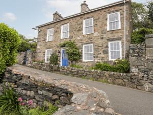 an old stone house with white windows and a stone wall at Bron Castell in Harlech