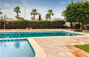 een zwembad in een resort met palmbomen bij 2 Bedroom Nice Home In Los Narejos in Los Narejos