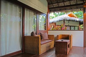 a porch with a wicker chair and a table at Last Frontier Beach Resort-Adults Only in El Nido
