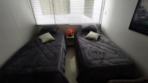 two beds in a small room with a window at APARTAMENTO CÓMODO, ILUMINADO Y CENTRAL EN MANIZALES in Manizales