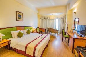 ニャチャンにあるヤサカ サイゴン ニャ チャン ホテル & スパのベッド、デスク、テレビが備わるホテルルームです。
