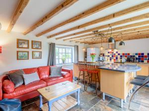 a living room with a red couch and a kitchen at Gables Cottage in Market Rasen