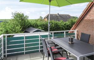 a patio table with an umbrella on a balcony at 2 Bedroom Cozy Apartment In Dagebüll in Dagebüll