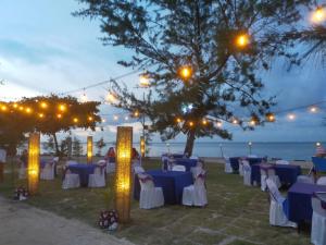 a group of tables and chairs with lights at Madu Tiga Beach and Resort in Tanjung Pinang  +74 photos