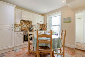- une cuisine avec des placards blancs, une table et des chaises dans l'établissement Bay View, à Brixham