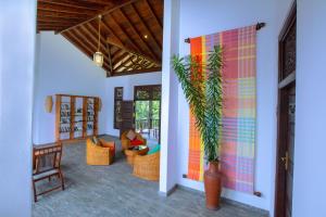 a hallway with a living room with chairs and a plant at Niyagama House in Galle