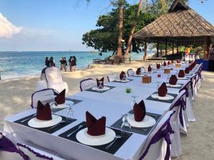 a row of tables on the beach with hats on them at Madu Tiga Beach and Resort in Tanjung Pinang