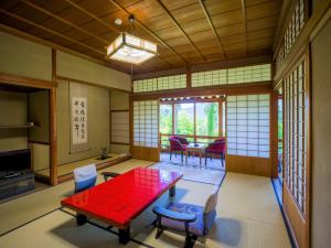 a living room with a red table and chairs at Yunoshimakan in Gero