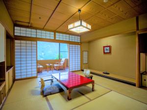 a living room with a red table in a room at Yunoshimakan in Gero