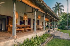 a house with a porch with benches and tables at Rice House in Habaraduwa