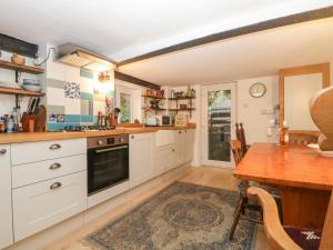 a kitchen with white cabinets and a wooden table at Teacher's Cottage in Taunton