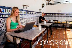 a woman sitting at a table with a laptop at Hostel Triana Backpackers in Seville