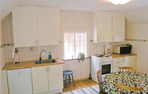 kuchnia z białymi szafkami, stołem i zlewem w obiekcie Amazing Home In Lttorp With Kitchen w mieście Gamleby