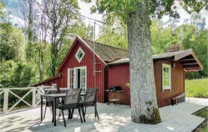ストレングネースにあるAmazing Home In Strngns With 3 Bedrooms, Sauna And Internetの木の前にテーブルと椅子が置かれた赤いキャビン