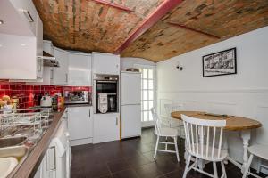 a kitchen with white cabinets and a wooden table at 3 Canalside Cottages in Towcester