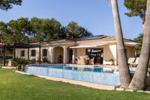 a villa with a swimming pool in front of a house at Luxurious villa Sol de Mallorca in Sol de Mallorca
