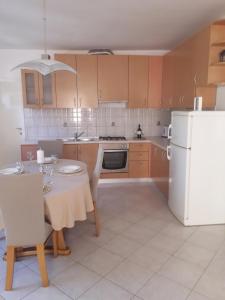 cocina con mesa y nevera blanca en Apartments Mirjana, en Sukošan