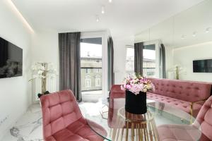 uma sala de estar com mobiliário rosa e uma mesa de vidro com flores em Apartamenty HashtagWilda_Apartament Złoty em Poznań
