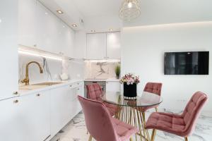 uma cozinha com uma mesa de vidro e cadeiras cor-de-rosa em Apartamenty HashtagWilda_Apartament Złoty em Poznań