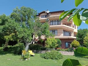 a large apartment building with a tree in the yard at Villa Prolet in General-Kantardzhievo