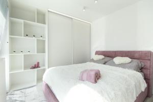 um quarto com uma cama rosa e paredes brancas em Apartamenty HashtagWilda_Apartament Złoty em Poznań