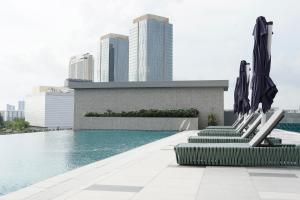 a swimming pool with chairs and umbrellas on a building at Opero Hotel Southkey Johor Bahru in Johor Bahru