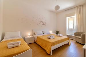 a bedroom with two beds and a chair at Casa vacanza i due ulivi in Modica