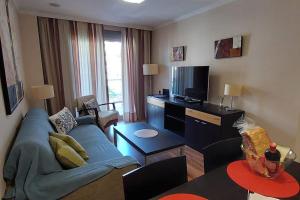 a living room with a blue couch and a tv at Elegante alojamiento con piscina a 200 m del mar. in Benalmádena