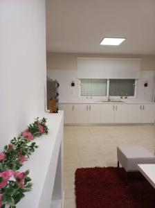 una gran cocina con armarios blancos y flores rosas en Grand Afroditi LUX en Pýrgos
